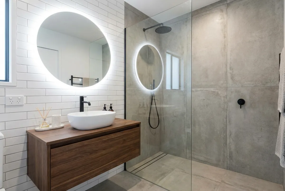 Modern bathroom with floating vanity, LED mirror, and glass shower