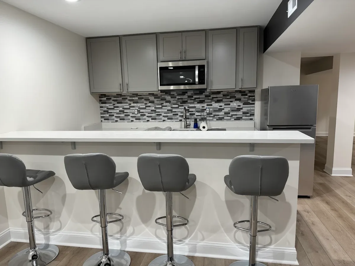 Basement remodel with kitchen bar, mosaic backsplash, and quartz counters