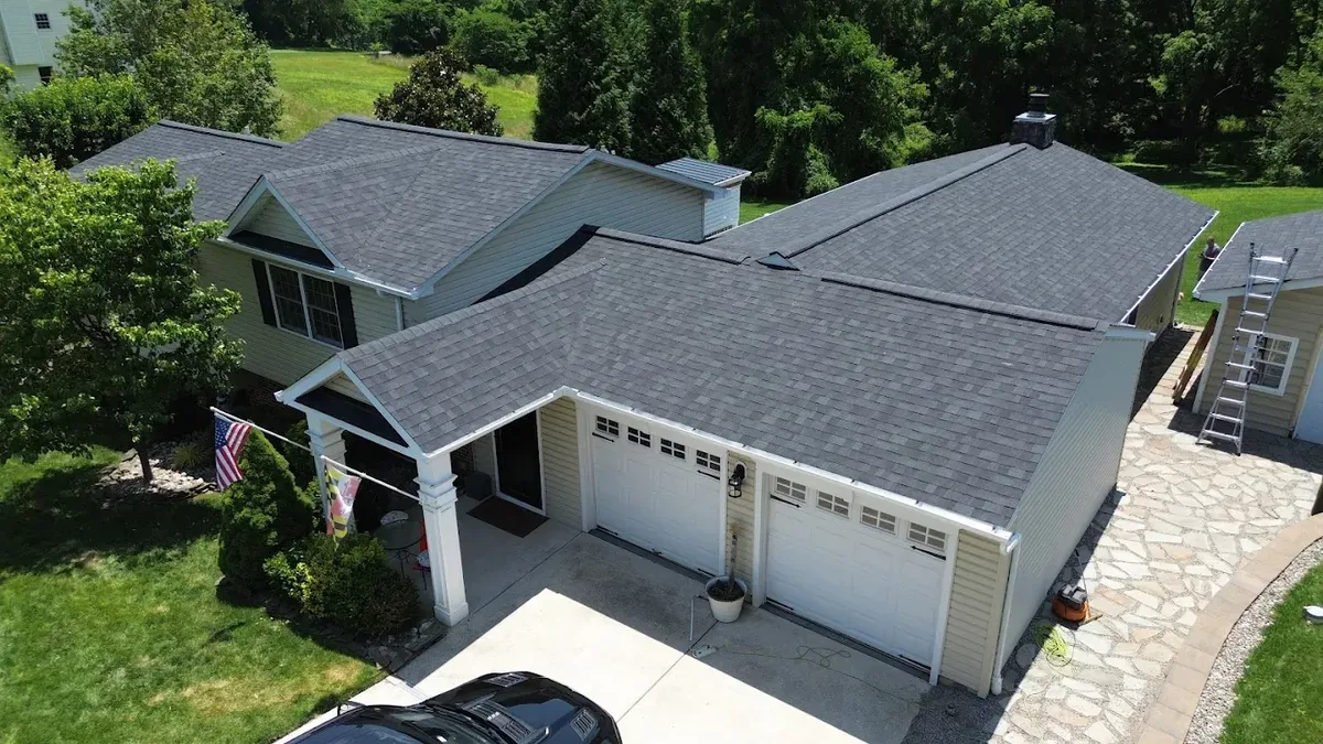 Aerial view of new shingle roof installation with Maryland flag