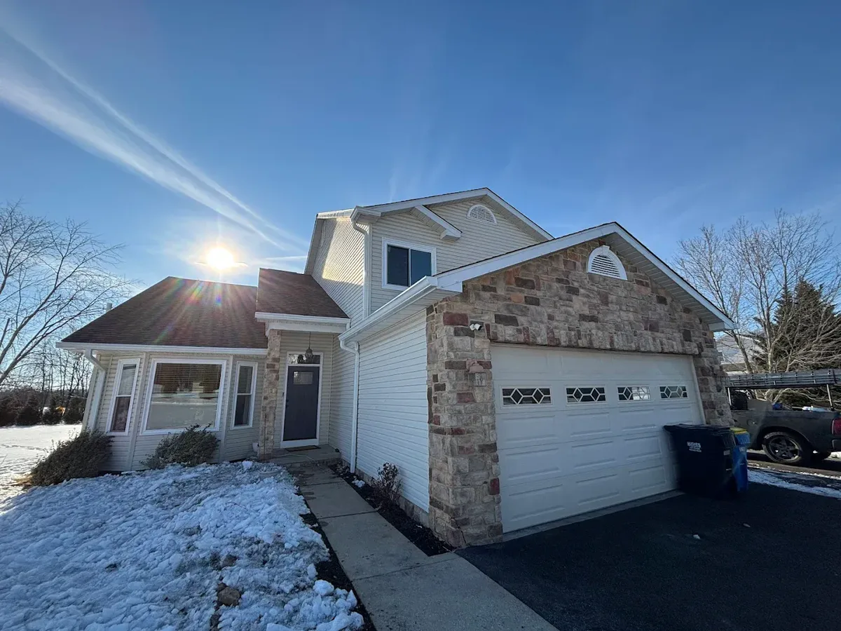 Home exterior with new siding, stone facade, and roof in winter