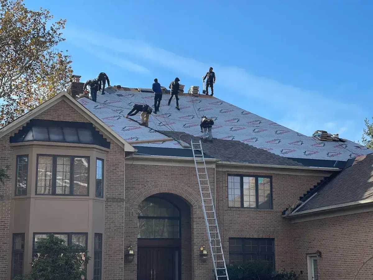 Crown Remodeling crew installing roof underlayment on brick home